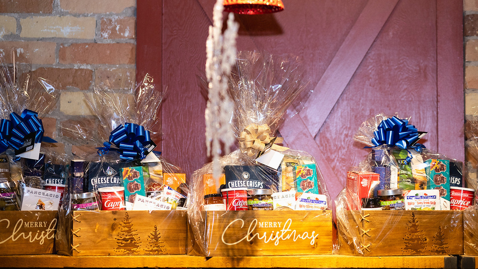 Gift baskets with Christmas-themed packaging against a brick wall.