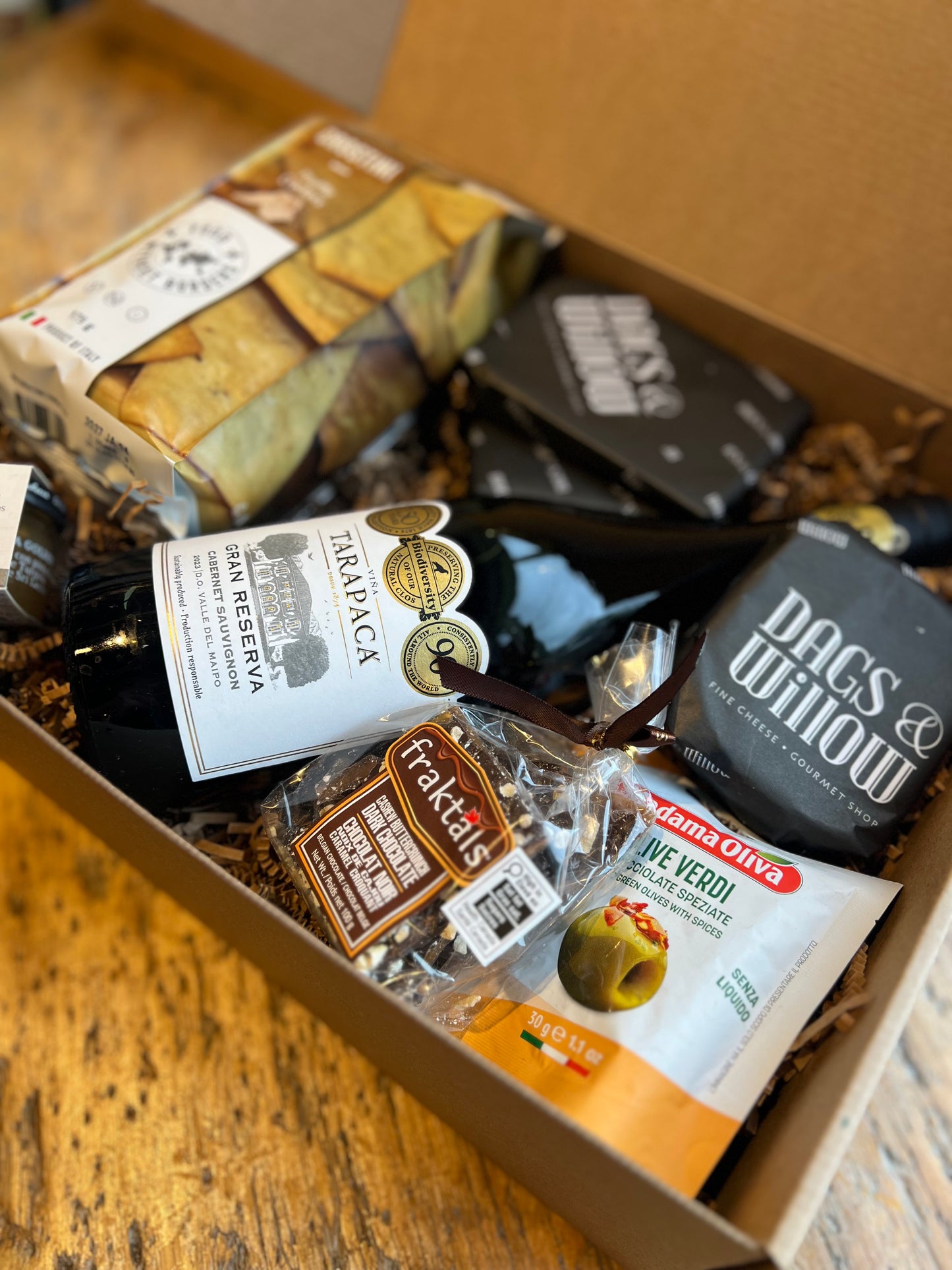 Open box containing various food items and products on a wooden surface